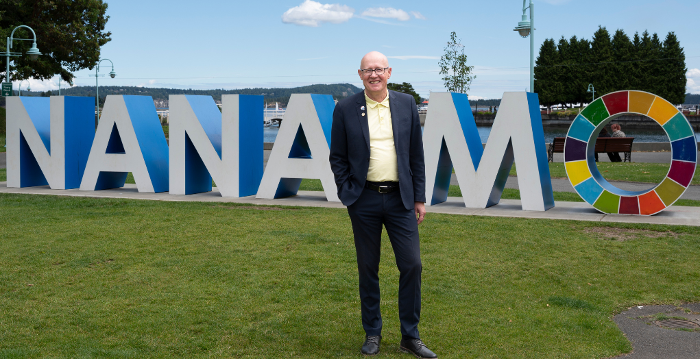 Ken Hammer stands in front of a 3-D Nanaimo sign --